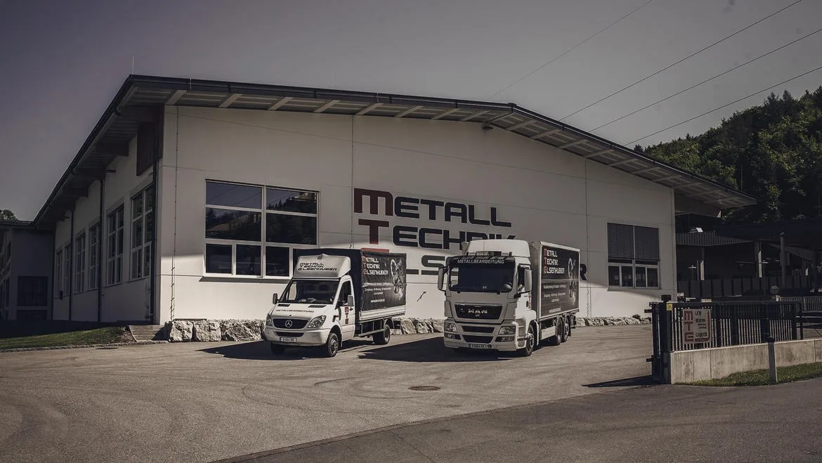 Beschriftete MTE-Halle mit zwei Firmen-LKW